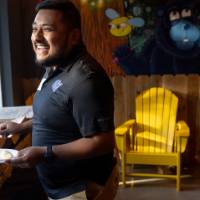 Man in black shirt with GV athletics logo. smiling as he holds plate
